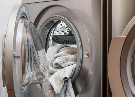 Öppen tvättmaskin i rostfritt med en handduk i.