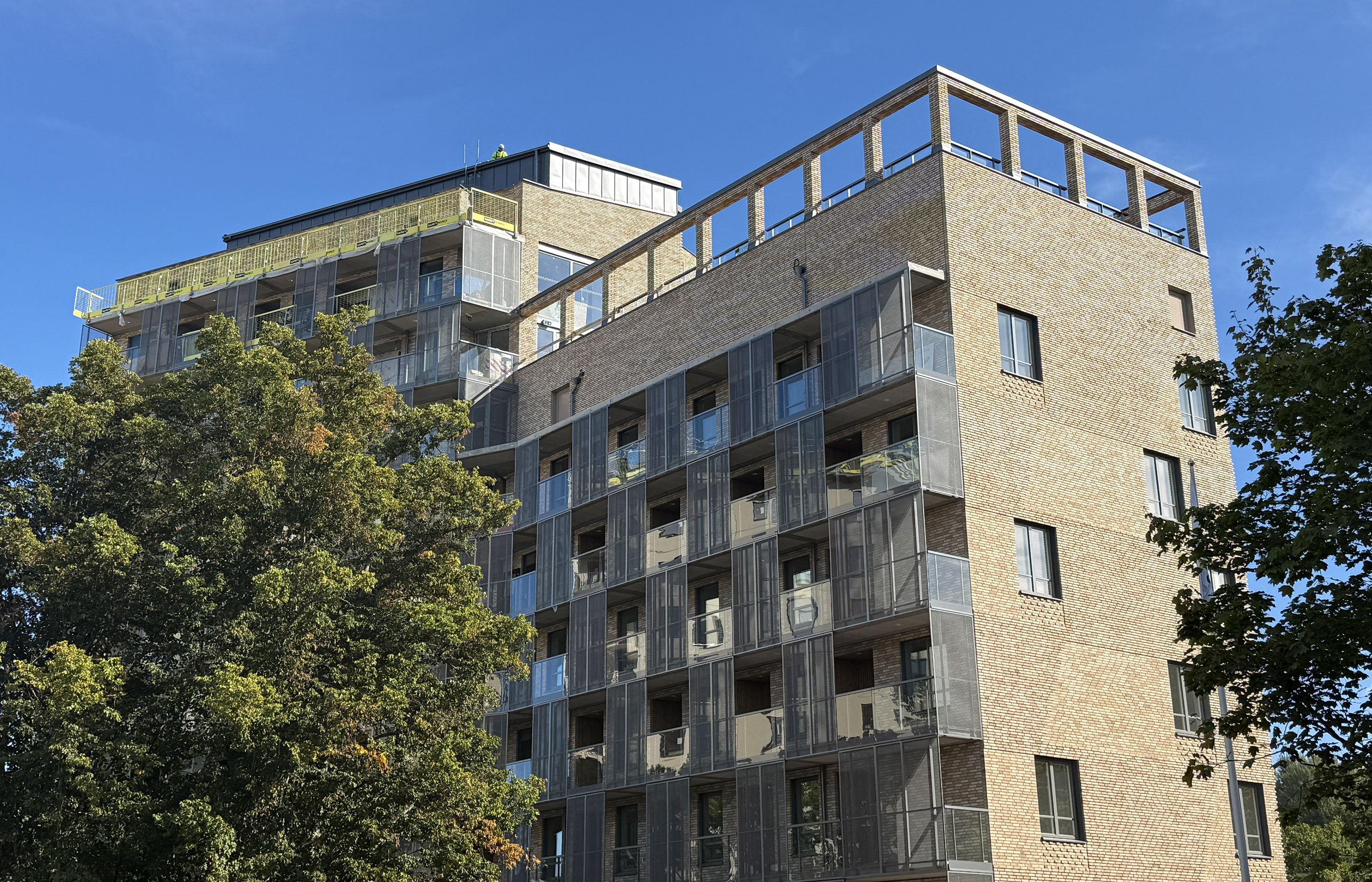 Hus under uppförande, med gul tegelfasad och inglasade partier.
