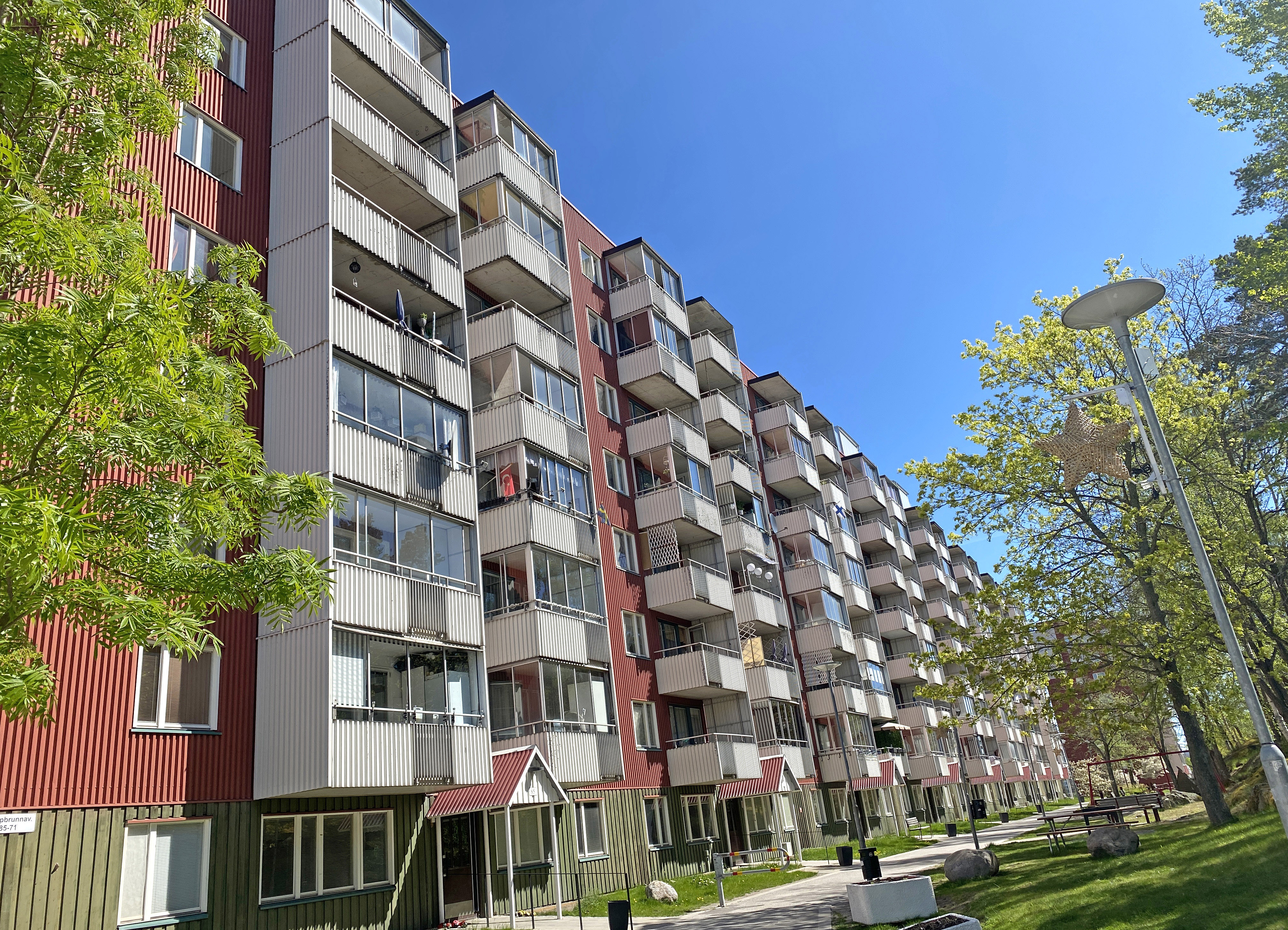 Rött långt 7-våningshus med grön sockel och vita balkonger.