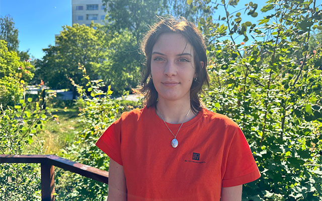 En tjej i orange t-shirt står framför ett träd