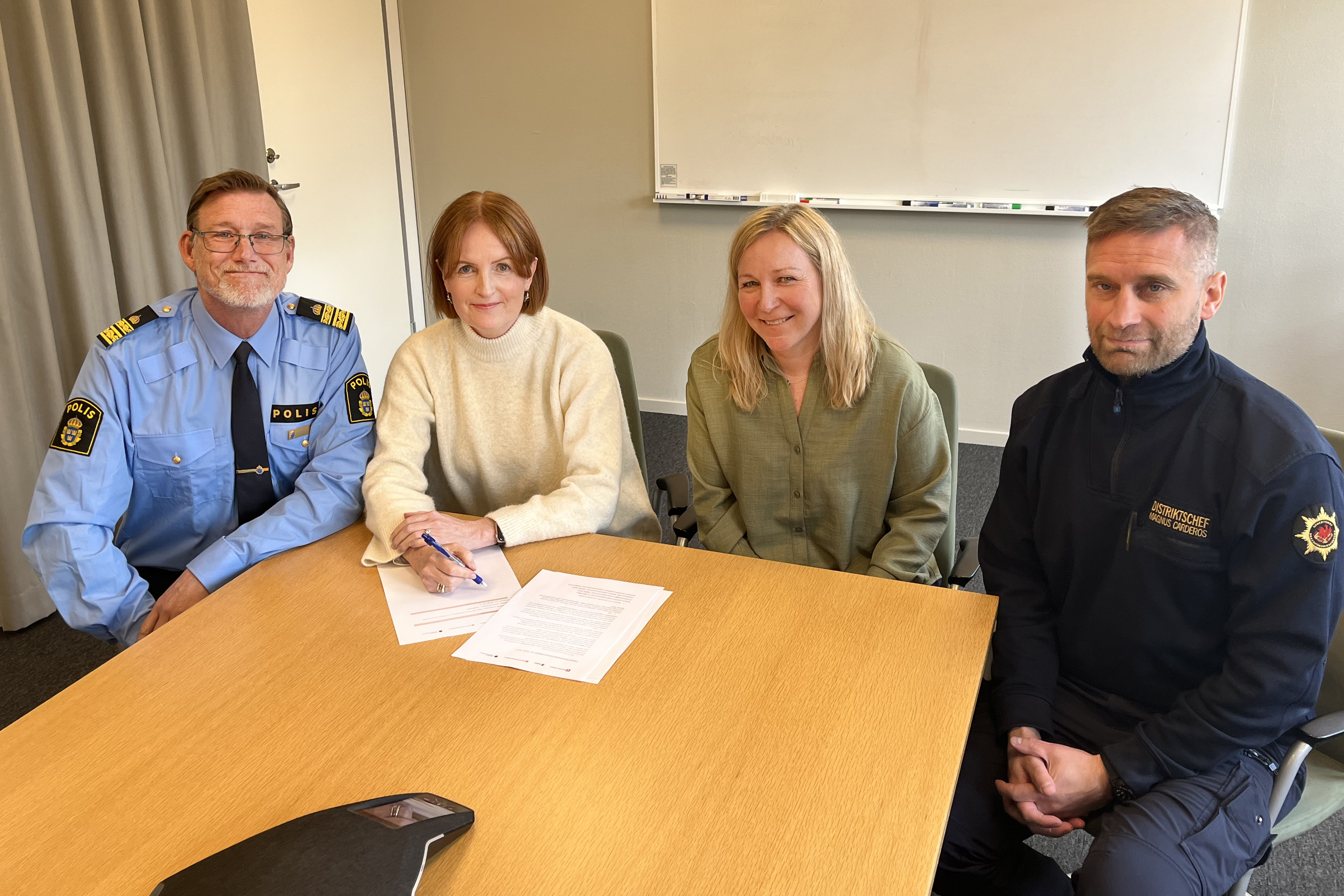 En man klädd i polisuniform, en kvinna i vit tröja, en kvinna i grön skjorta samt en man i räddning