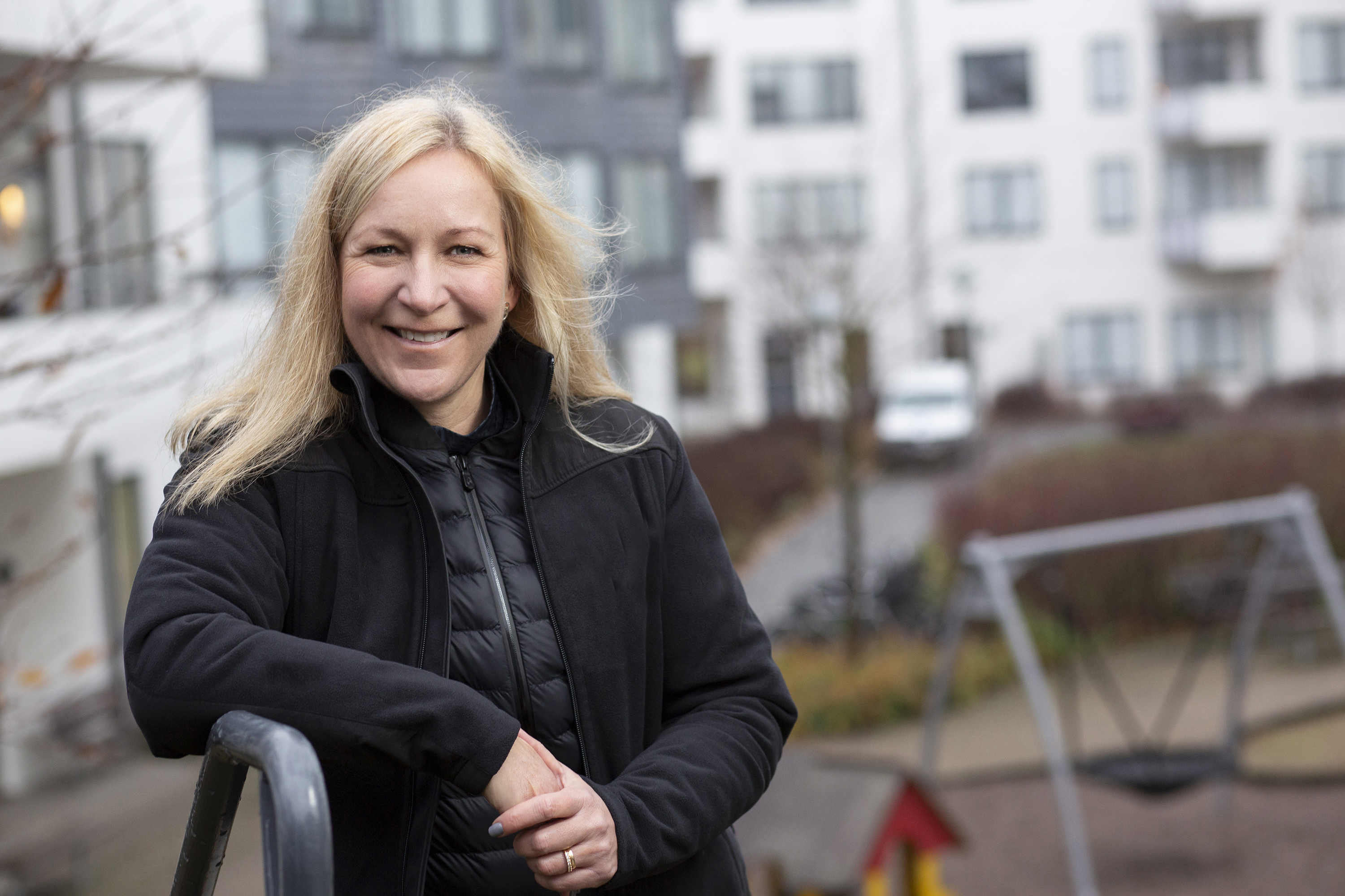 Porträtt av leende kvinna stående framför vita hus.