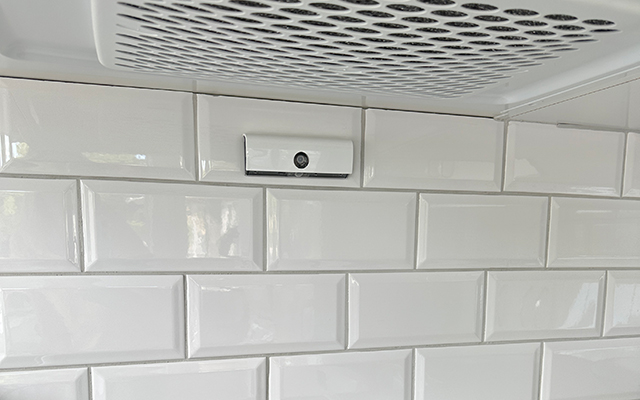 Spisvakt under en köksfläkt. I bakgrunden vitt rektangulärt fasat  blankt kakel.