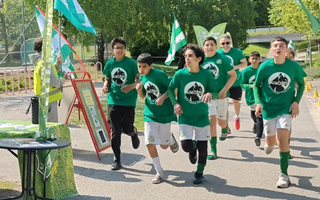 En grupp barn i gröna tröjor springer.