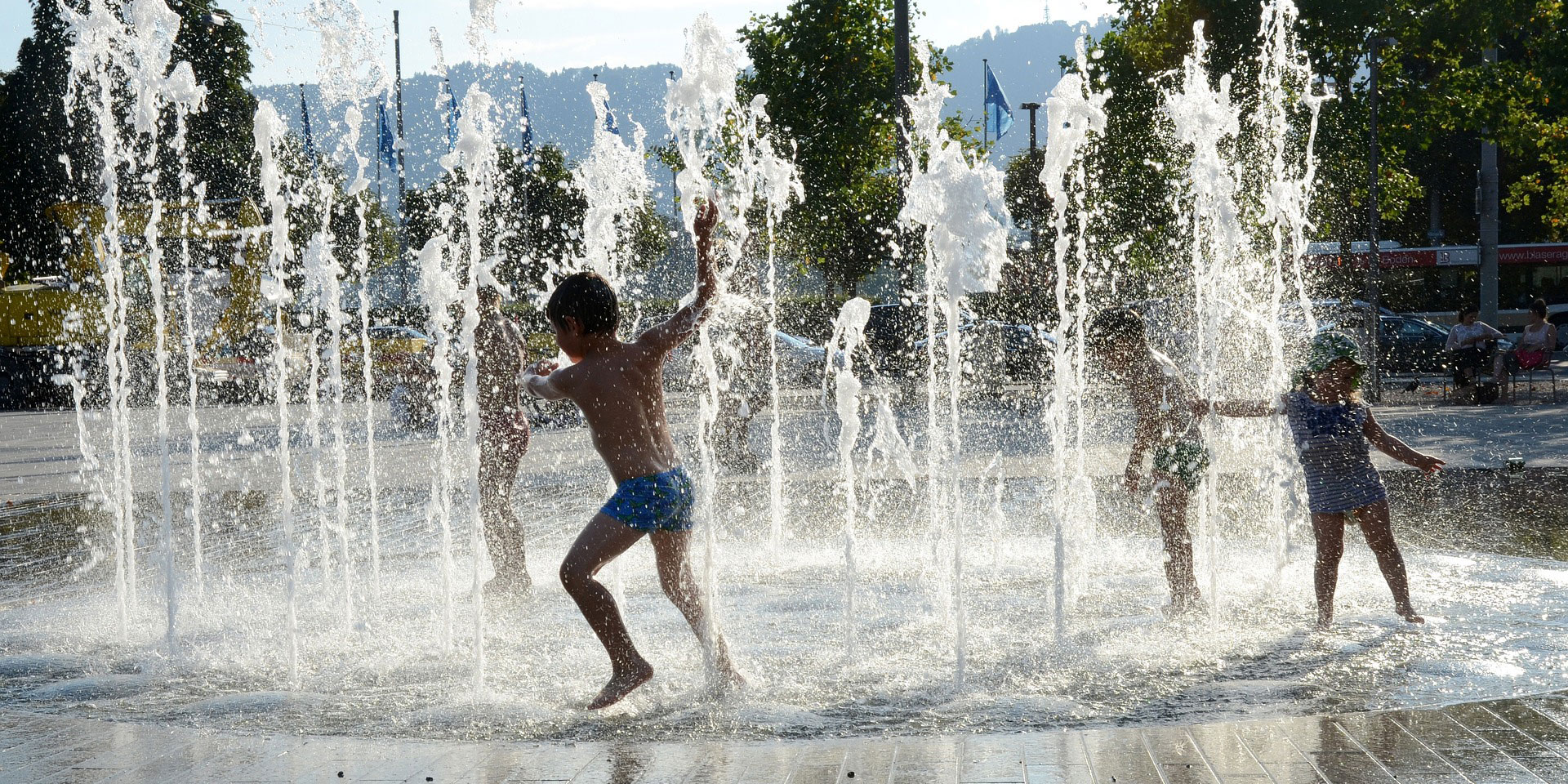 Tre barn leker i en fontän