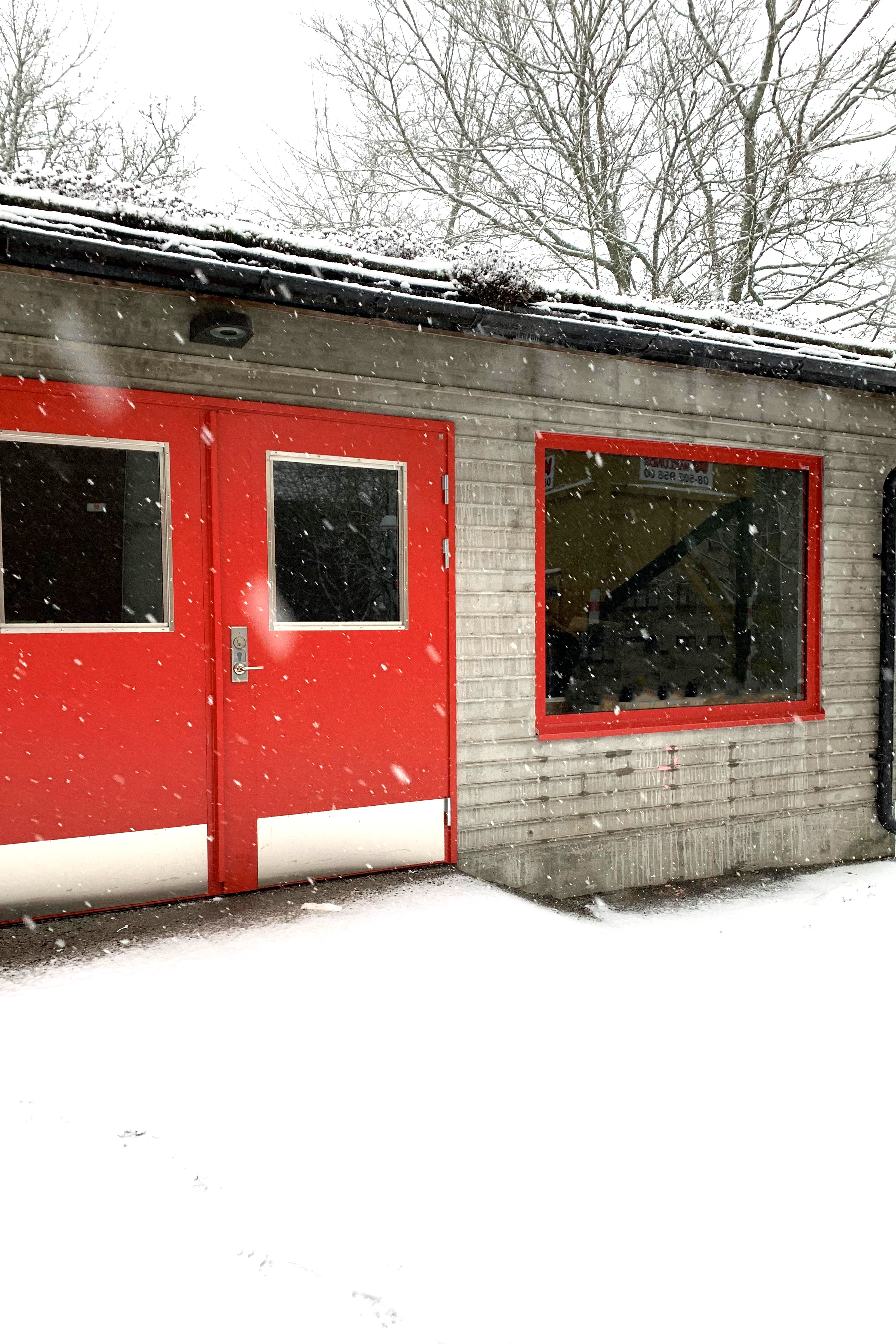 Miljöhuset på Värdshusvägen med röda dörrar och fönster