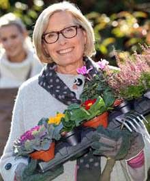 En kvinna som håller i krukor med blommor.